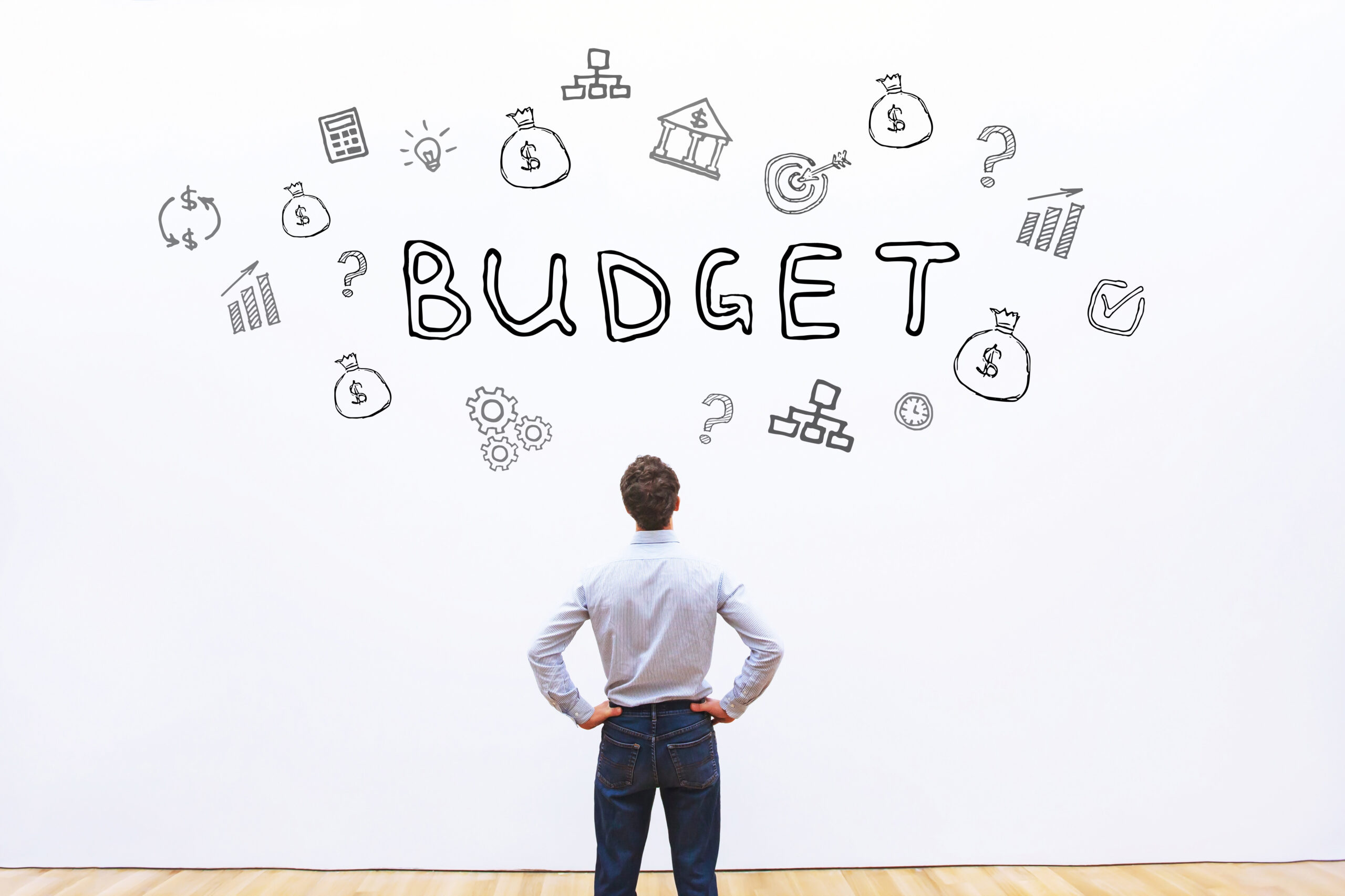 Man standing in front of a wall with budget.