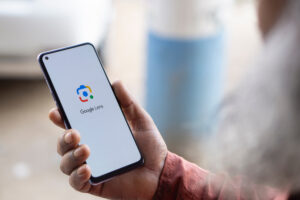 Person holding a smartphone displaying the Google Lens logo on the screen.