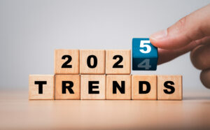 Wooden blocks spell out "2024 TRENDS" with a hand placing a final block featuring the number 5.