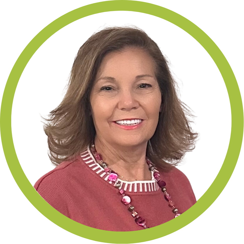 A woman with shoulder-length brown hair, wearing a pink top and beaded necklace, smiles at the camera. The image is framed by a green circular border.
