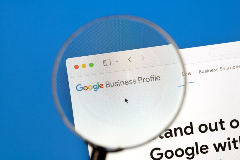 A magnifying glass focuses on the Google Business Profile updates for home services page displayed on a computer screen with a blue background.