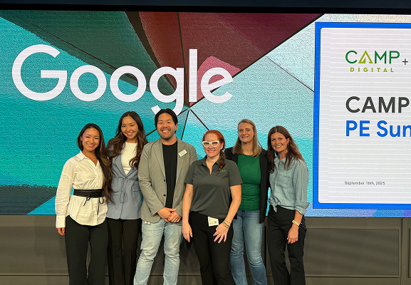 Six people stand together in front of a Google sign and a presentation screen that reads "CAMP+ PE Summit" at an indoor event.